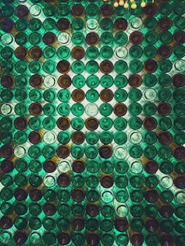 Vibrant artistic display of green and brown glass bottles creating an abstract pattern viewed from below.