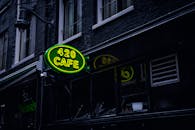 阿姆斯特丹的建筑立面上，绿色霓虹灯标志“420咖啡馆”营造出充满活力的城市氛围