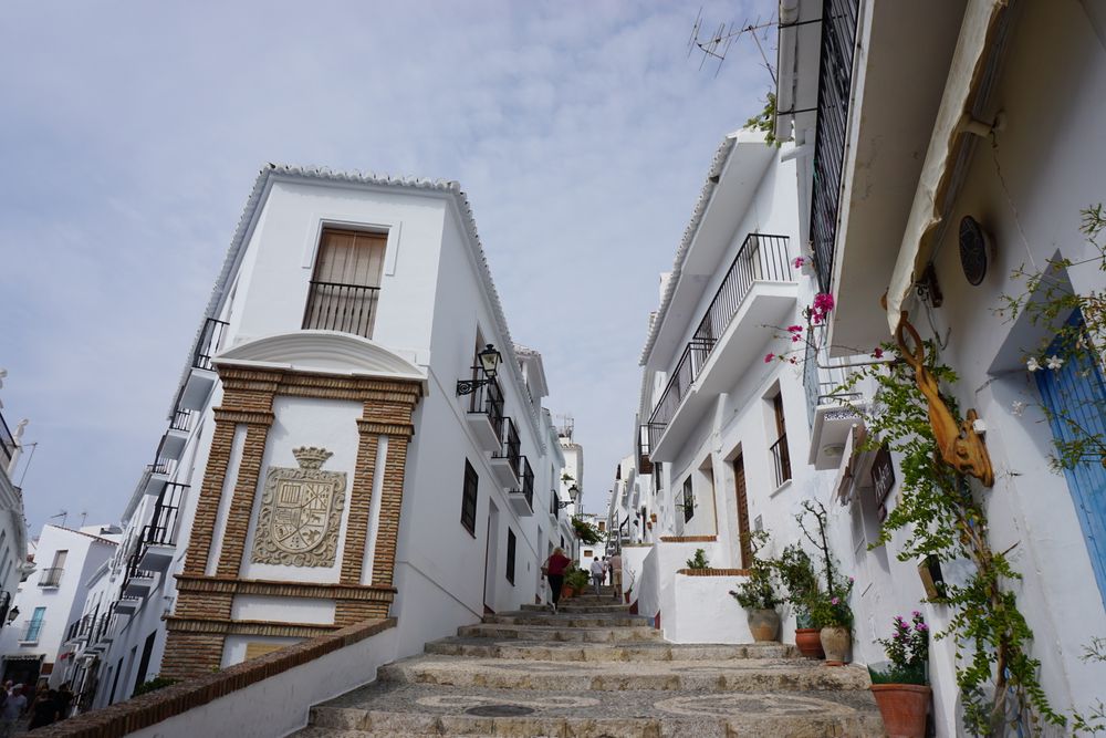 Străduță albă îngustă cu ghivece de flori într-un sat andaluz