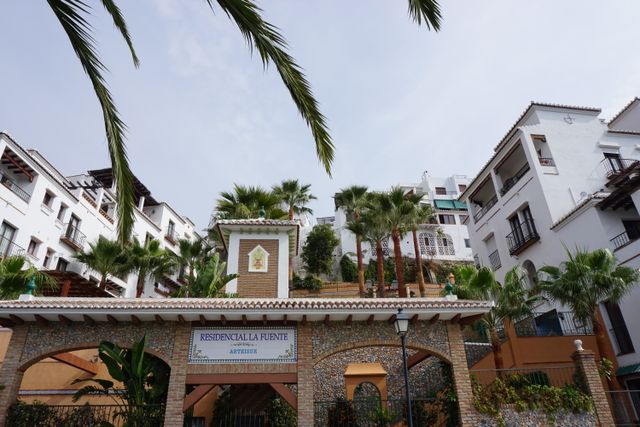 Mediterranean-style residential buildings and palm trees, representing UK-resident landlords' overseas rental property
