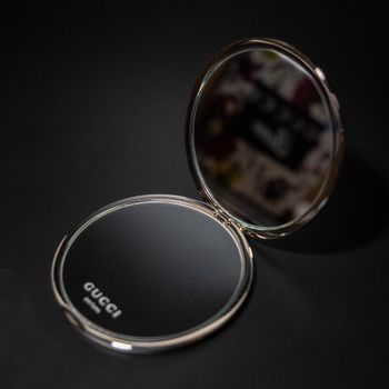 Stylish Gucci compact mirror with reflection, elegant design.