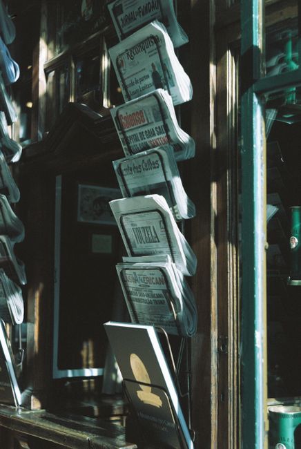 A nostalgic view of a newspaper stand in a sunlit alley in Lisbon, showcasing vintage print media.