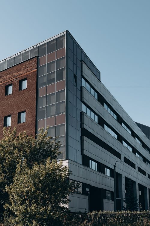 Free Contemporary urban building blending brick and metal architecture with greenery. Stock Photo