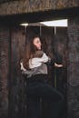 一位黑发女子的随意肖像站在华丽的木制门旁边，带有泥土、质朴的感觉