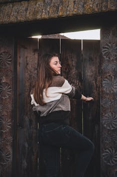 一位黑发女子休闲地站在华丽的木门旁，带着朴实、质朴的感觉