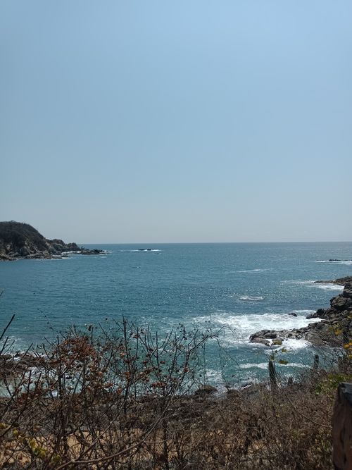 Free Calm coastal scene with clear blue ocean waves gently crashing against rocky shore. Stock Photo