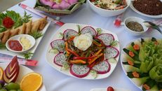 Vibrant display of Asian dishes and fresh fruit platter with dragon fruit, vegetables, and sauces.