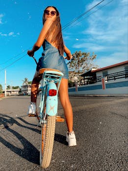 一个穿着休闲服的女人，在灿烂的夏日阳光下，于空旷的街道上摆出骑自行车的姿势