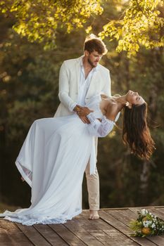 A groom holds his bride gracefully during an outdoor wedding ceremony.