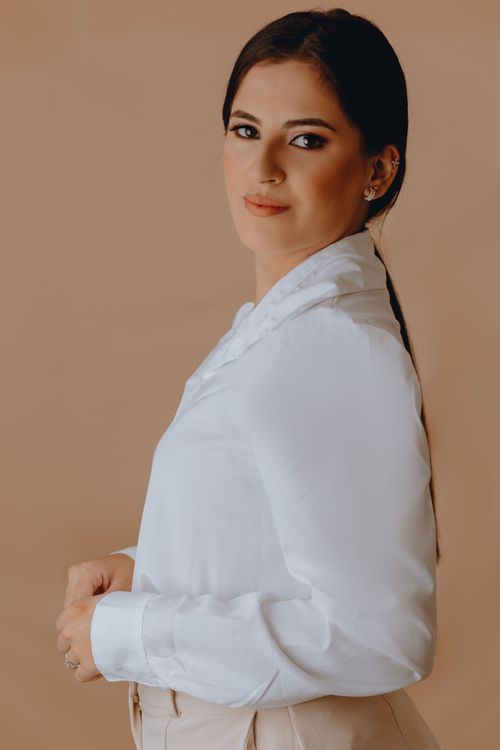 Free Sophisticated portrait of a young woman dressed in a white shirt against a neutral background. Stock Photo