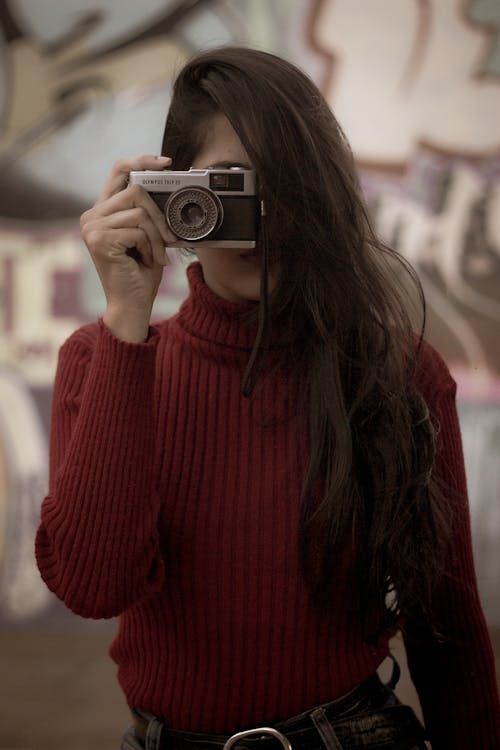 Selective Focus Photo of Woman in Red Pull-neck Sweater Holding Film Camera