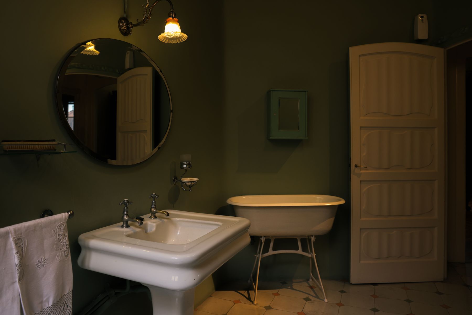 Warm classic bathroom with layered evening lighting and a freestanding bath