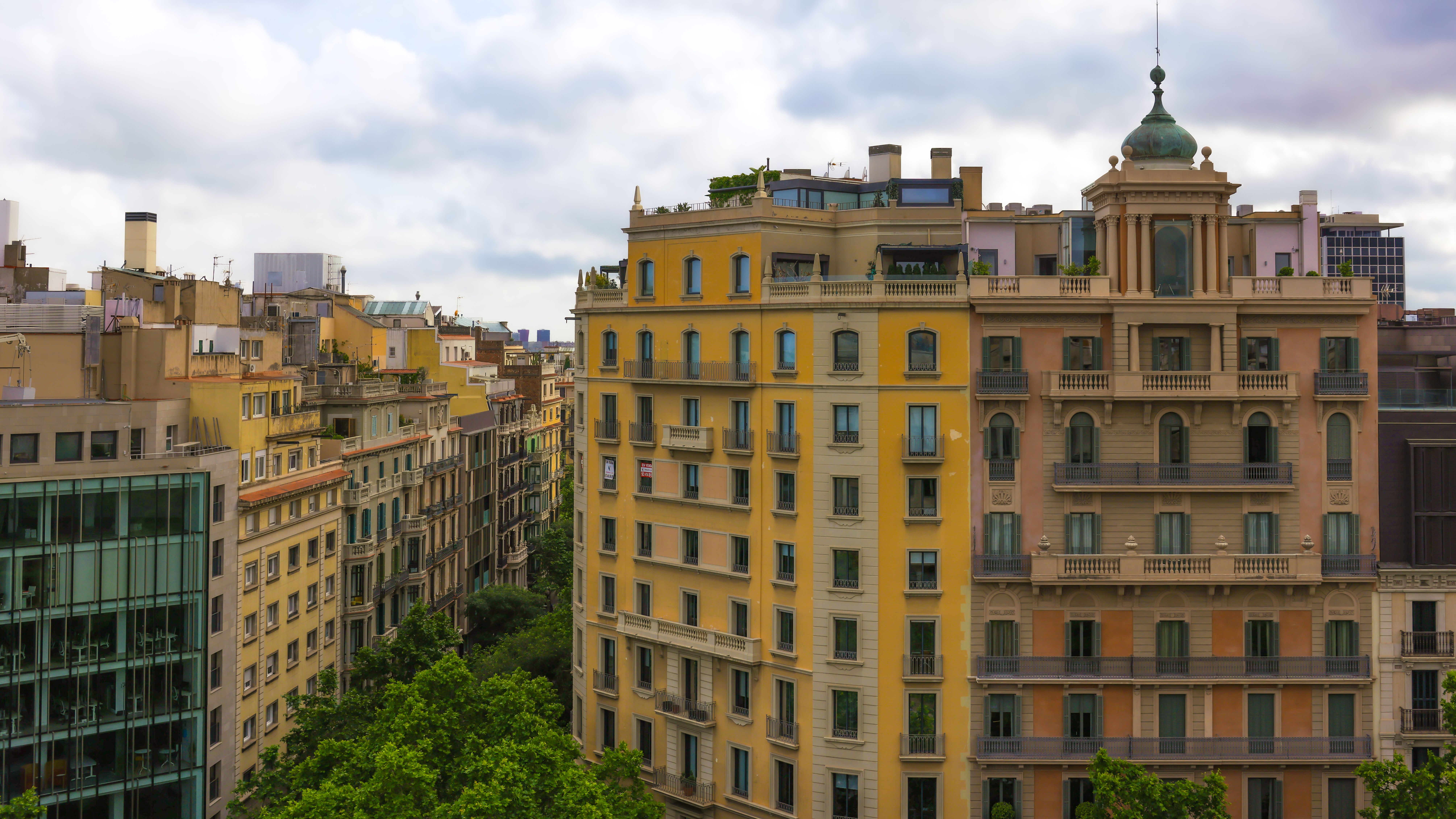 A stunning view of Barcelona's iconic architecture, showcasing vibrant buildings with a backdrop of clouds.