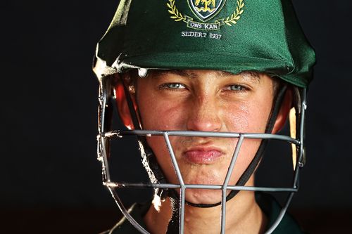 Free Focused young cricketer wearing a green helmet, preparing for the game. Stock Photo