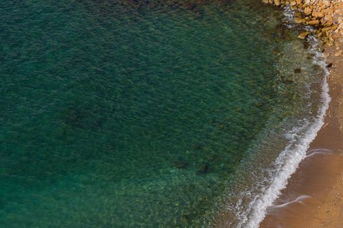 Free Beautiful aerial view of clear turquoise water meeting a sandy beach. Ideal for travel and nature themes. Stock Photo