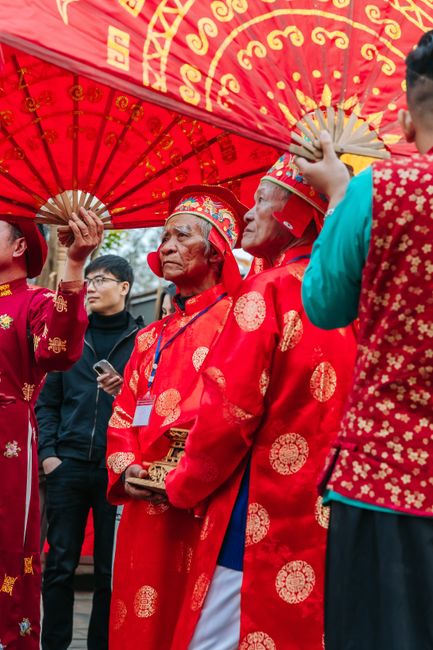 Elderly men in vibrant traditional attire at an Asian cultural festival.