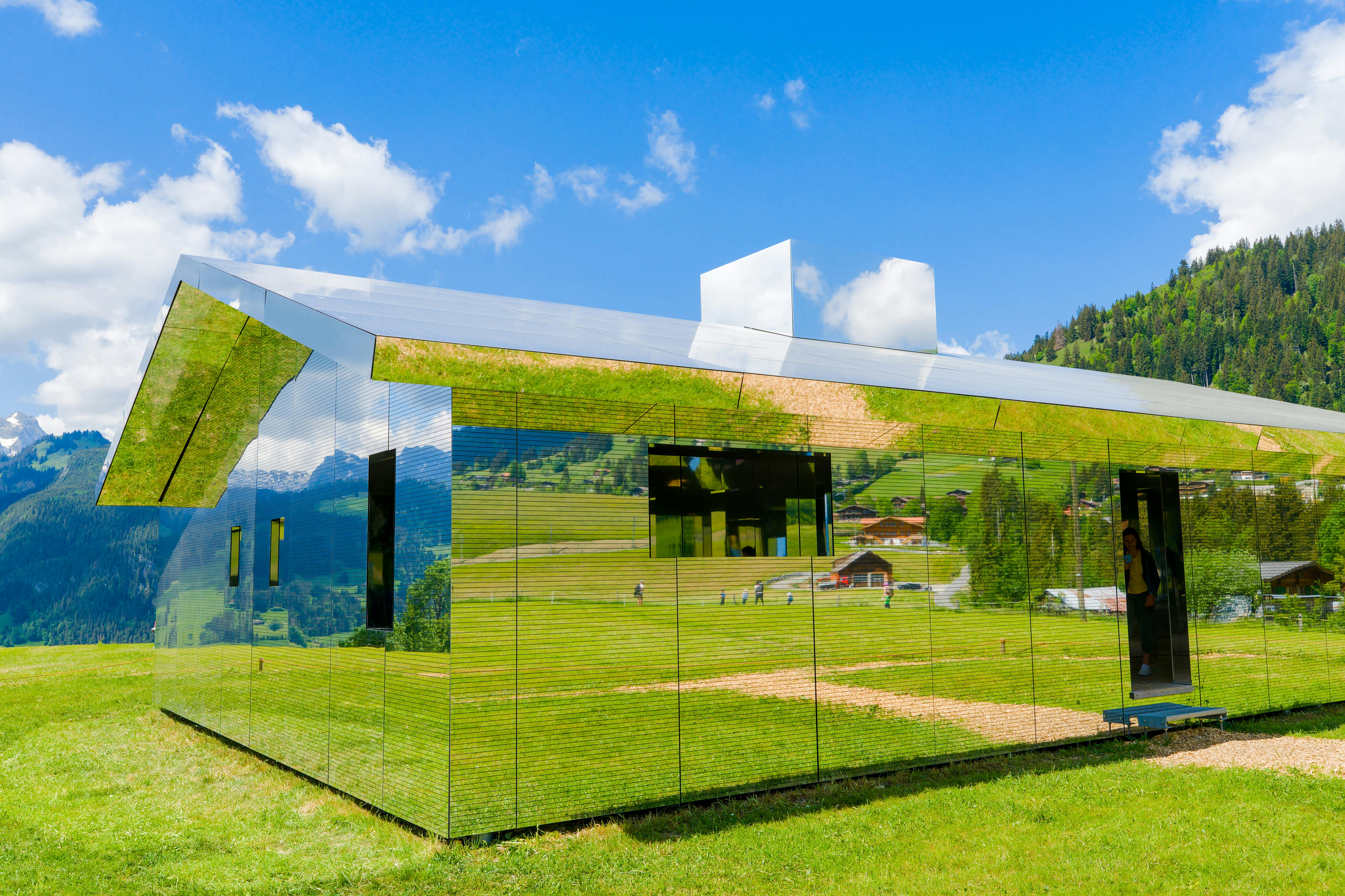 Reflective architectural house in Saanen, Switzerland with scenic mountain view.