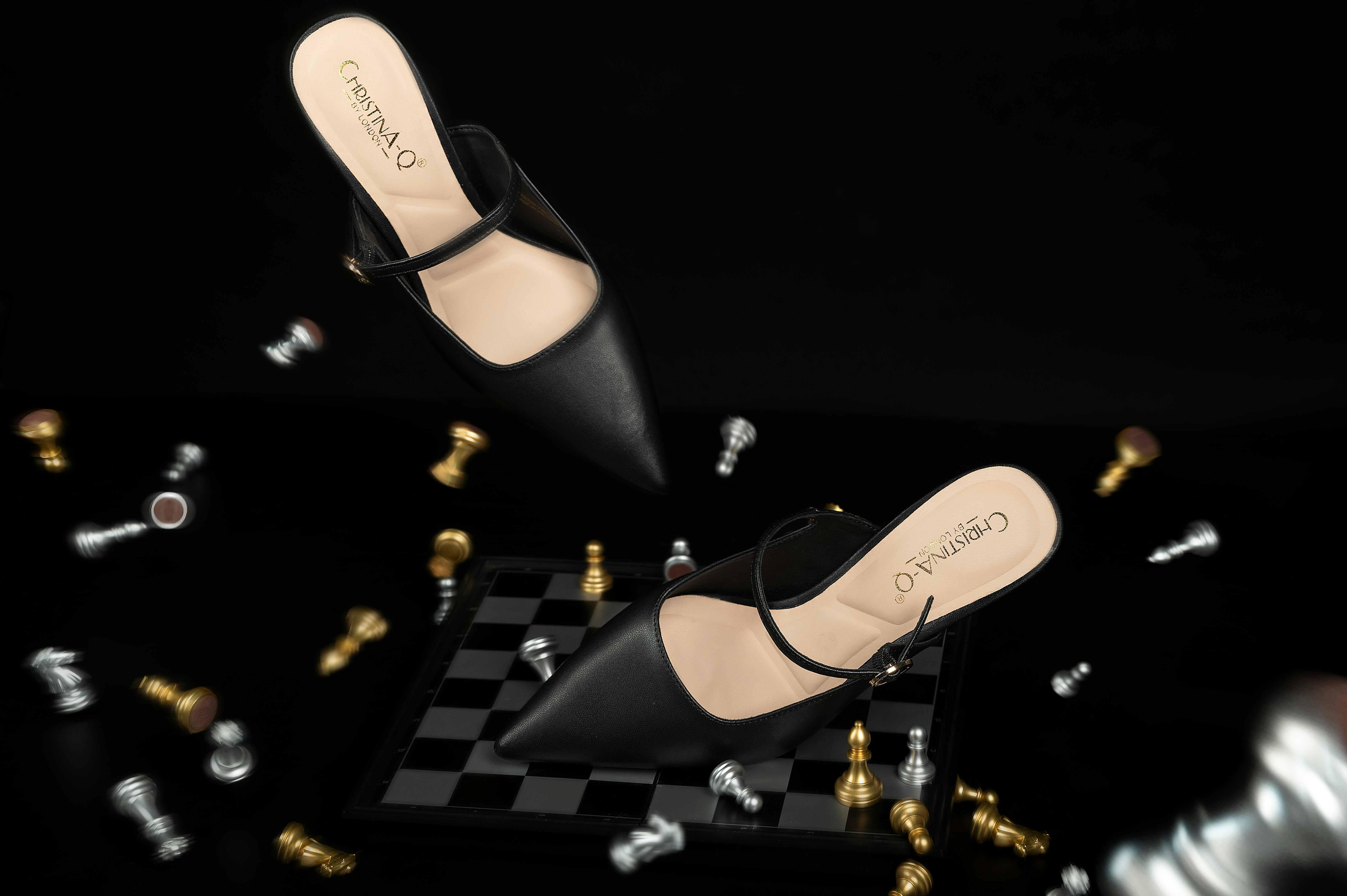 Free Stylish black high heels hover over a chessboard, blending fashion and strategy. Stock Photo