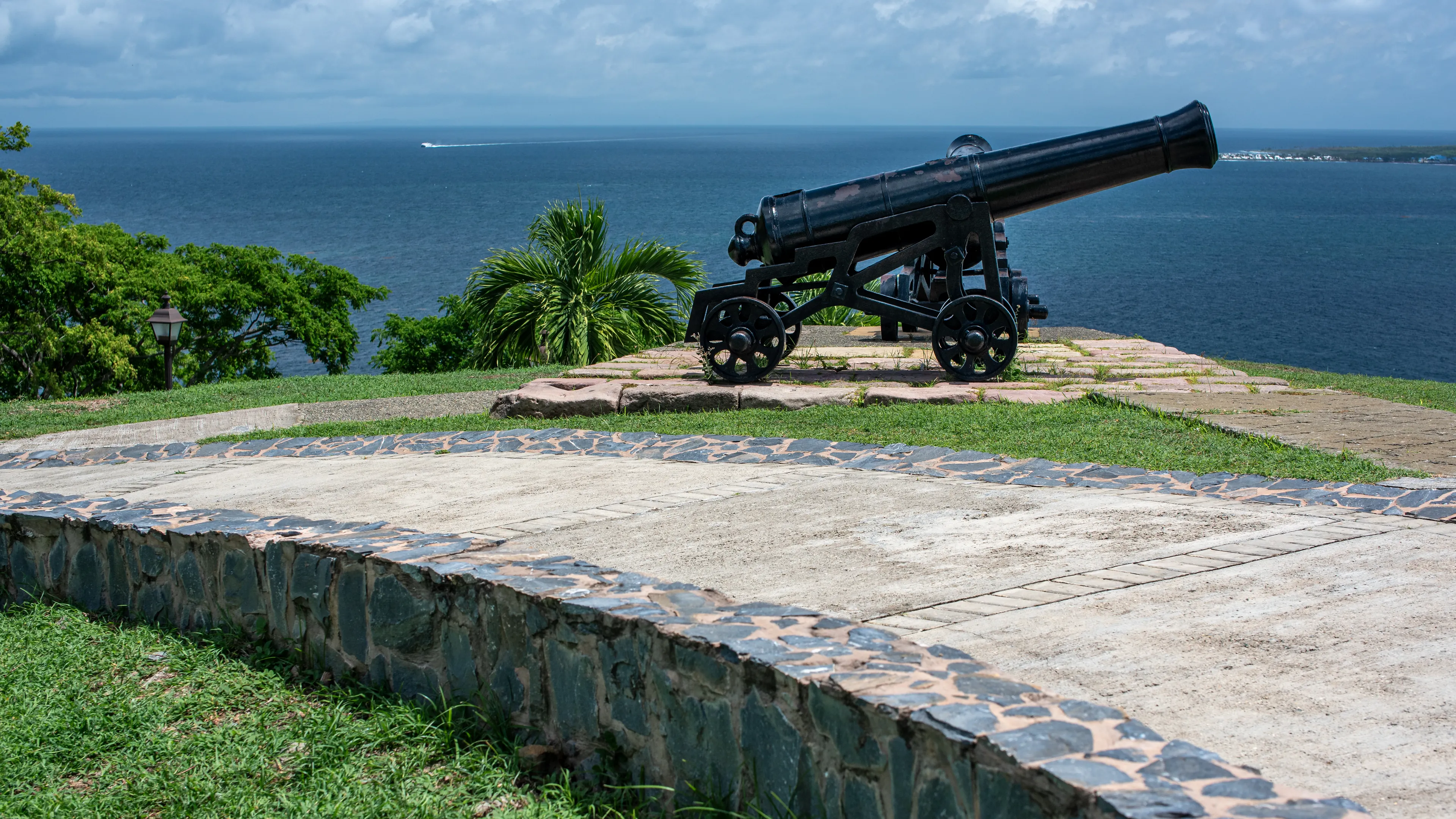 Cannon at Fort King George, Tobago, overlooking the azure Caribbean Sea under a bright sky.