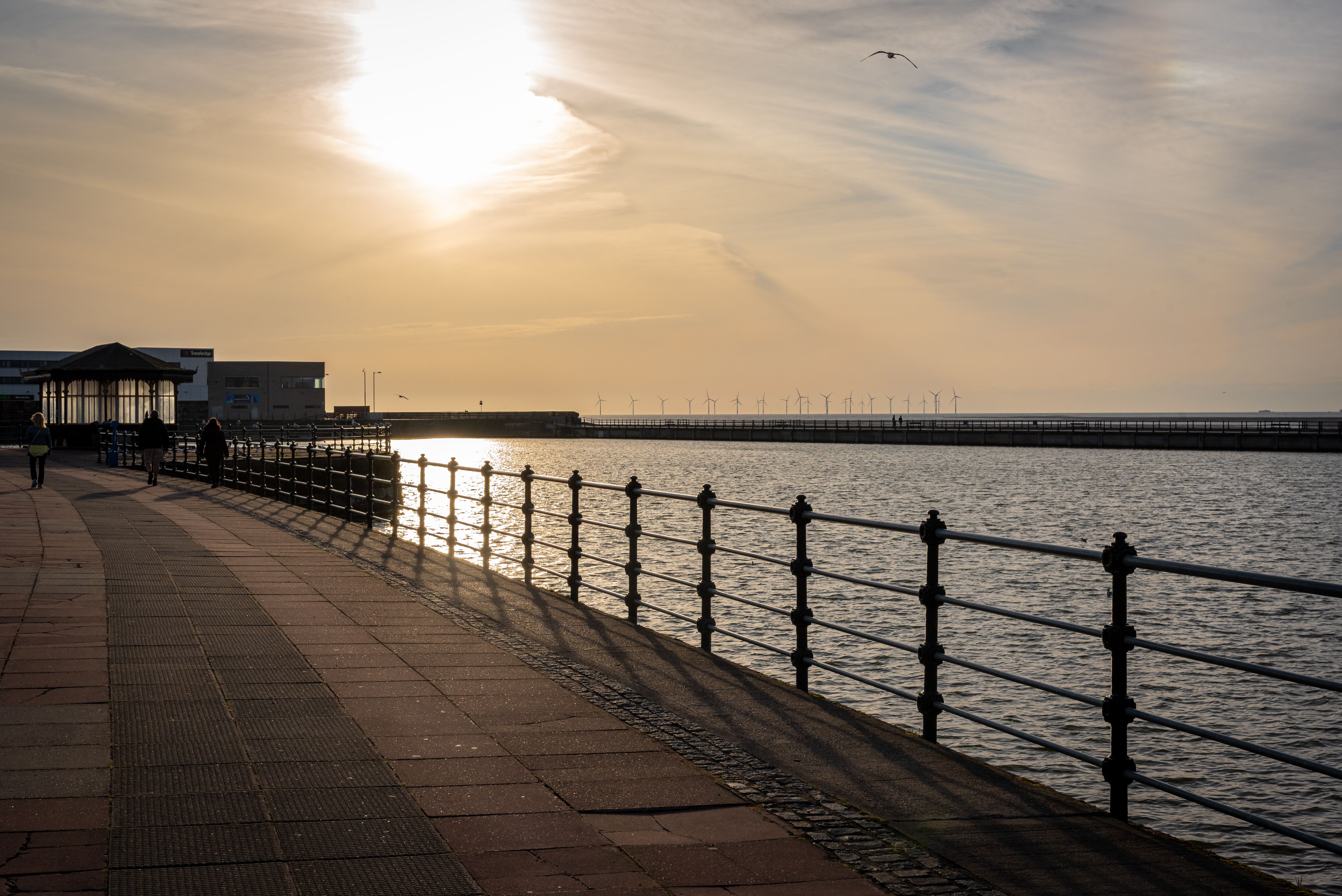 Beautiful sunset view at Wallasey promenade with distant wind turbines on the horizon.