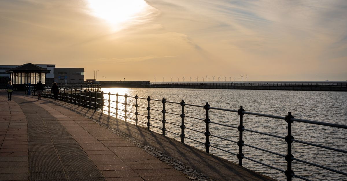 Beautiful sunset view at Wallasey promenade with distant wind turbines on the horizon.
