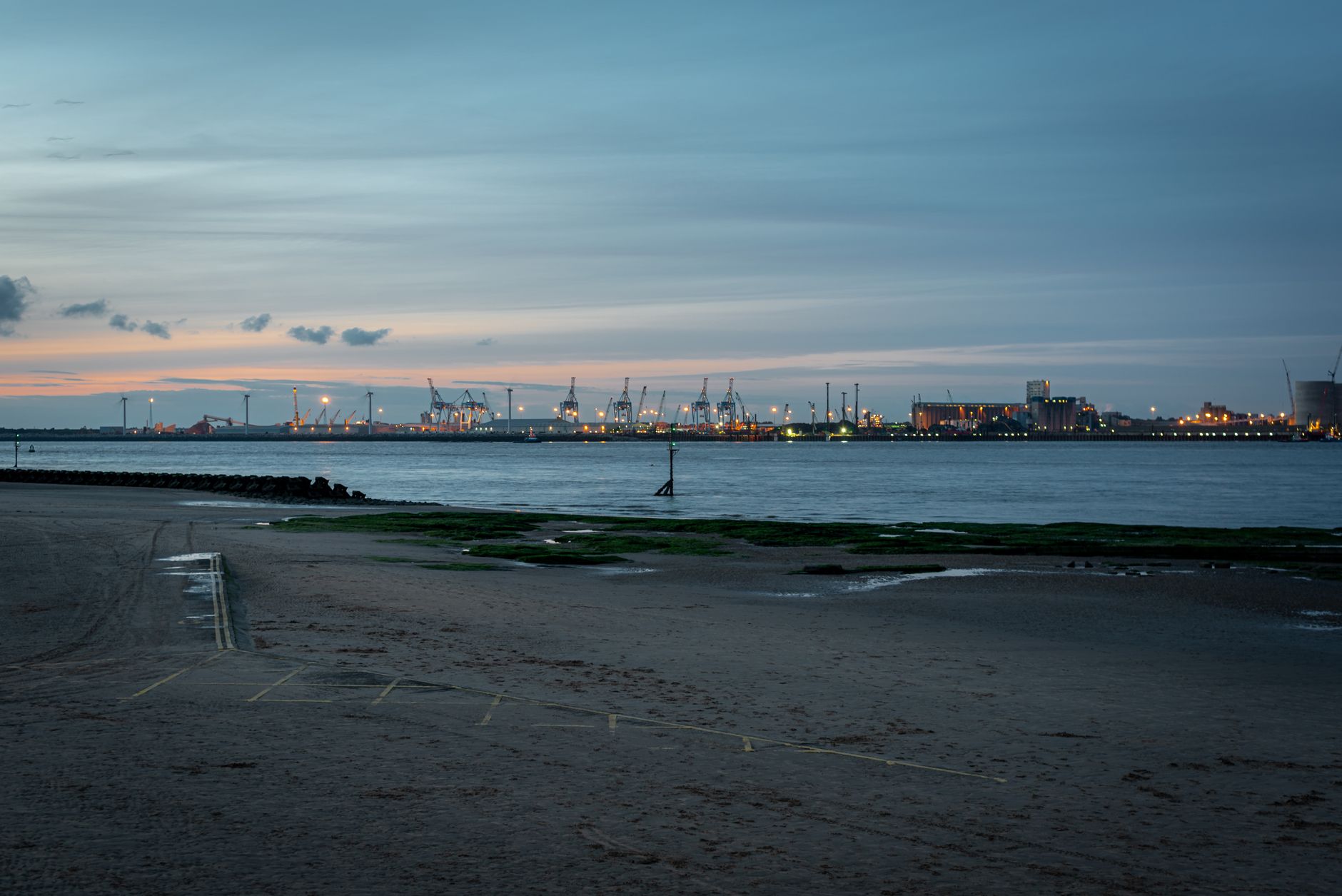 A serene view of New Brighton Beach with the shipyard at dusk, captured in England.