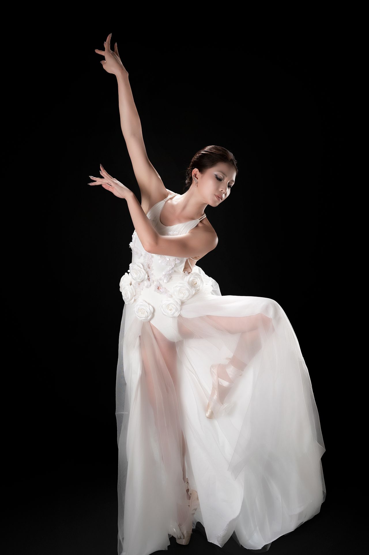 Graceful ballet dancer in a flowing white dress on a dark background