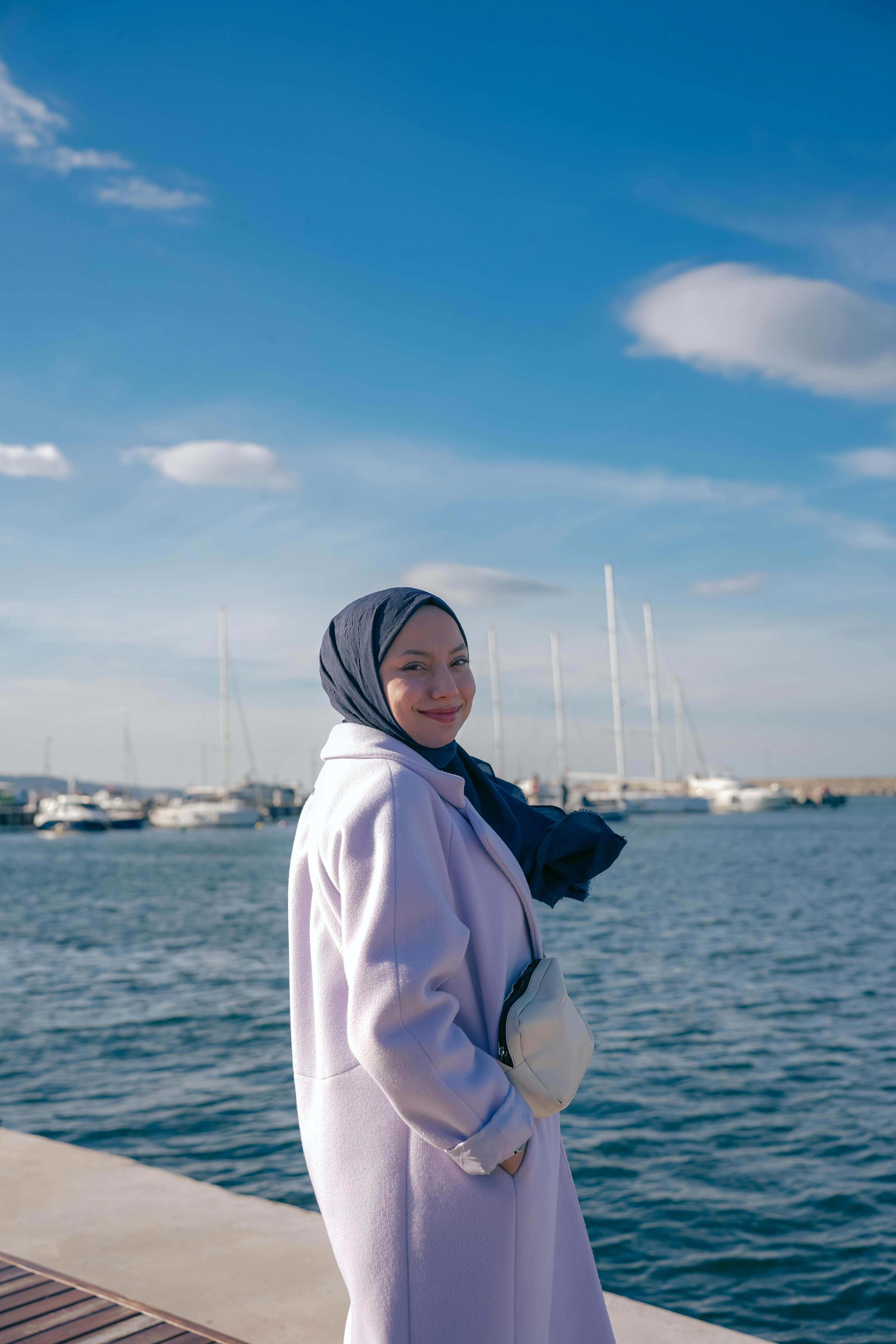 Smiling woman in a lavender coat by the clear blue sea in Şile, Istanbul.