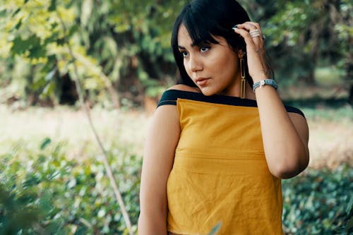 Free Selective Focus Photo of Woman in Yellow and Black Sleeveless Top Posing While Looking Away Stock Photo