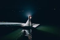 夜晚的码头上，新娘和新郎相拥的身影倒映在水中，勾勒出浪漫的轮廓