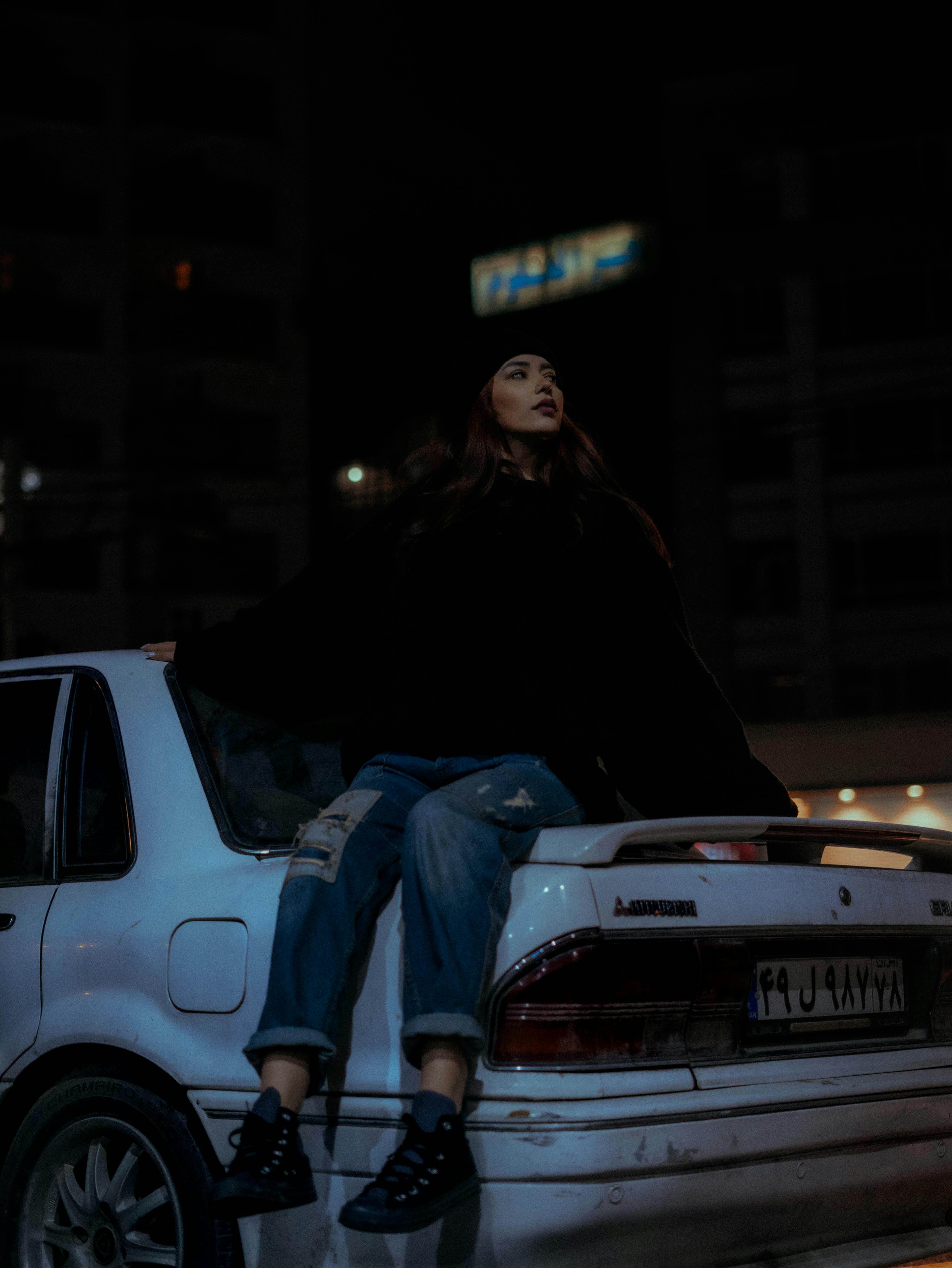 urban night scene with woman posed on car