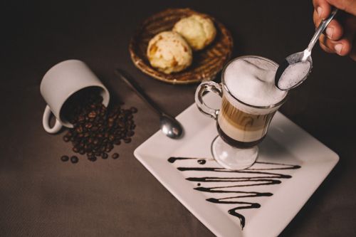 Free Elegant tabletop coffee setup with biscuits, coffee beans, and cream decoration. Stock Photo