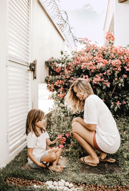 A mother and daughter bond in a vibrant garden filled with flowers, enjoying leisure time.