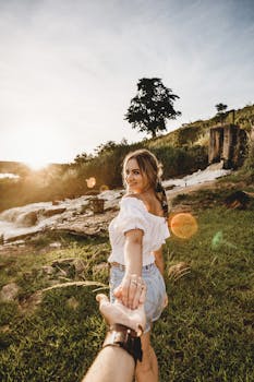 一对夫妇在风景如画的户外环境中，手牵手享受着瀑布旁阳光明媚的一天