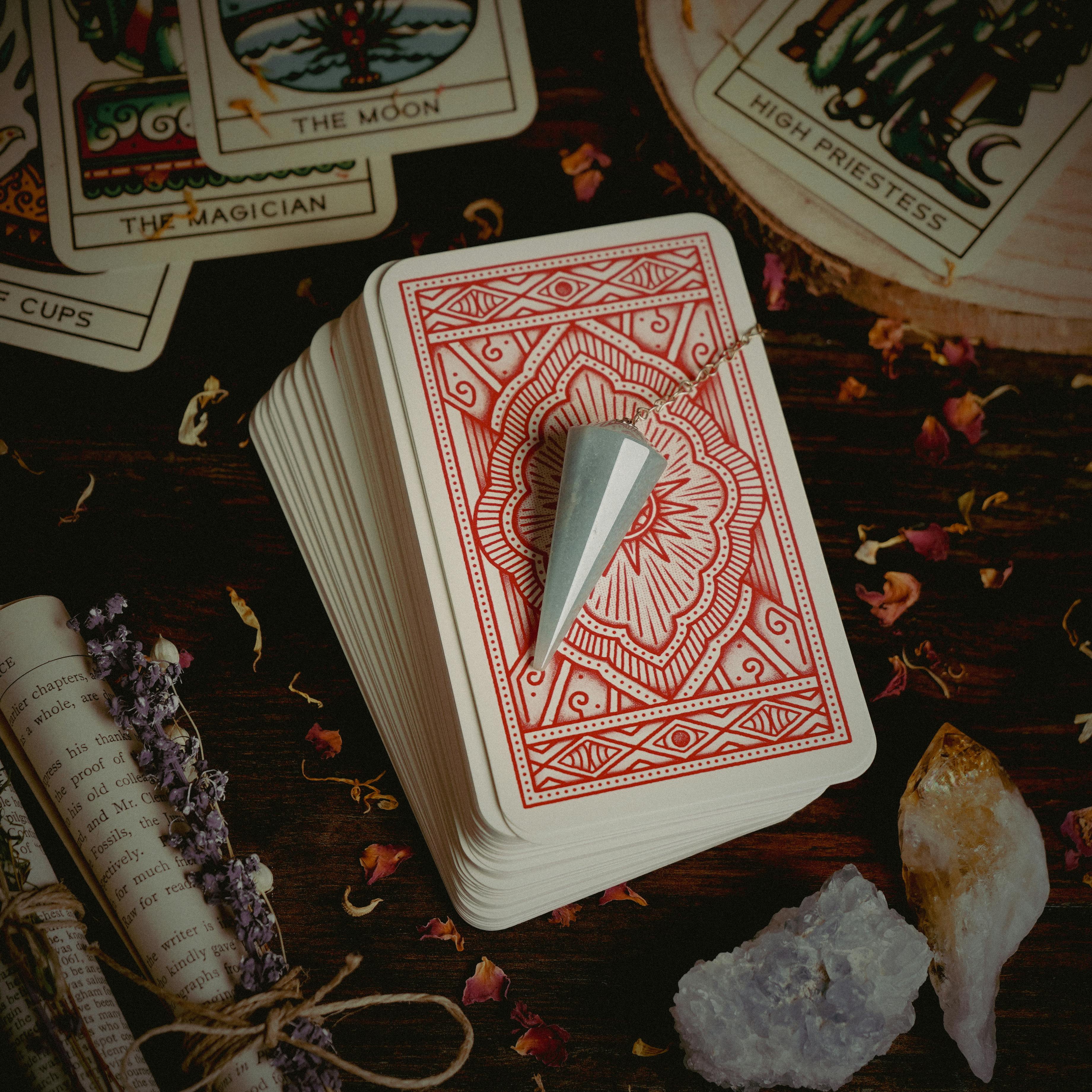 A top view of tarot cards with crystals and a pendulum, perfect for spiritual and divination practices.