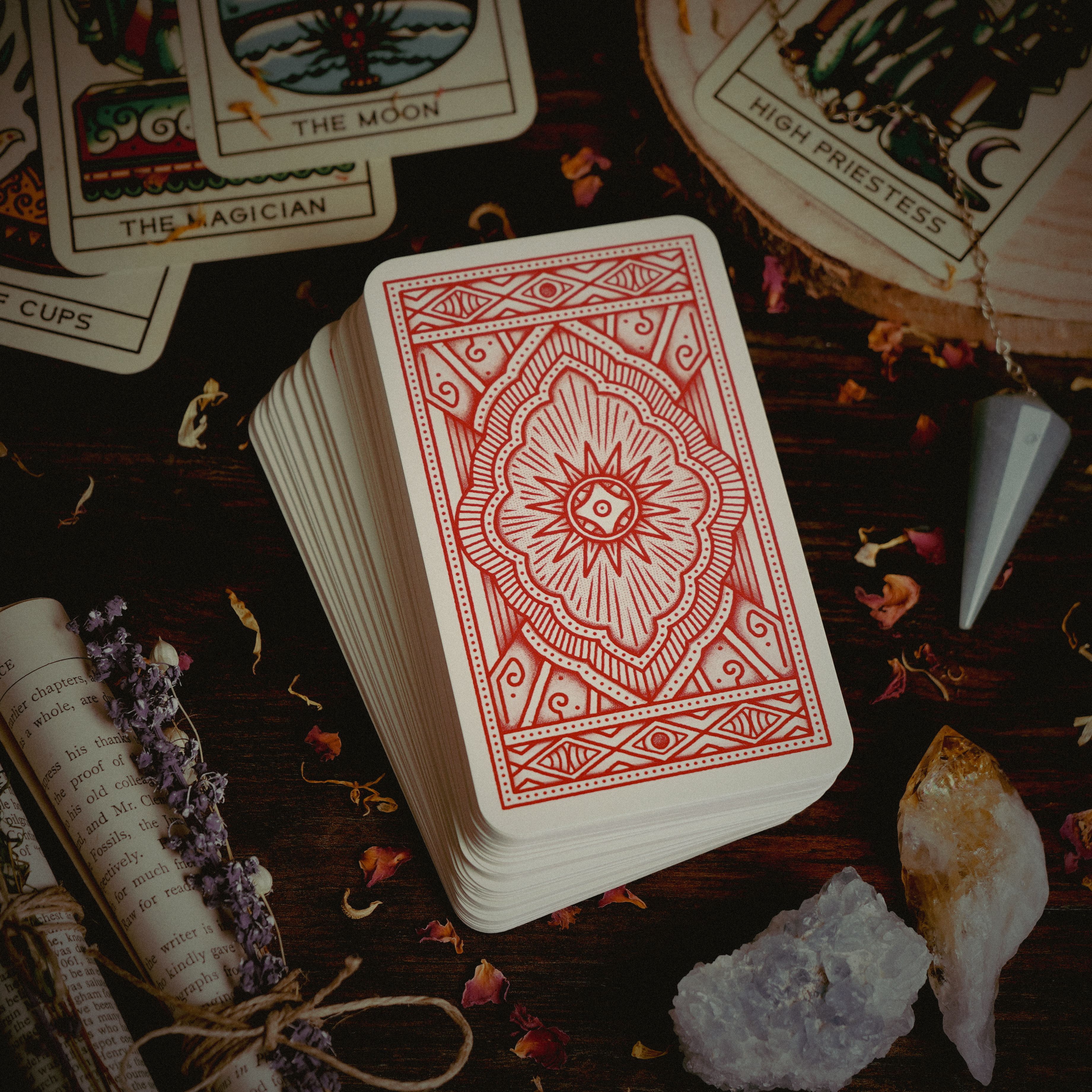 Stack of tarot cards with crystals and pendulum for divination and spiritual rituals.