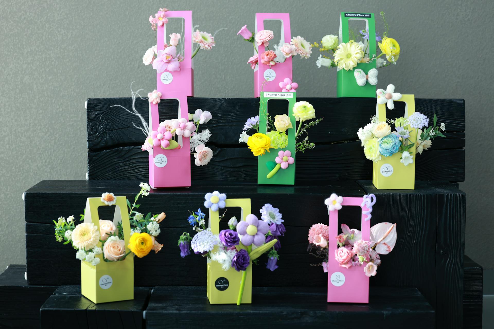 Vibrant flower arrangements in colorful gift boxes on a dark wooden background.