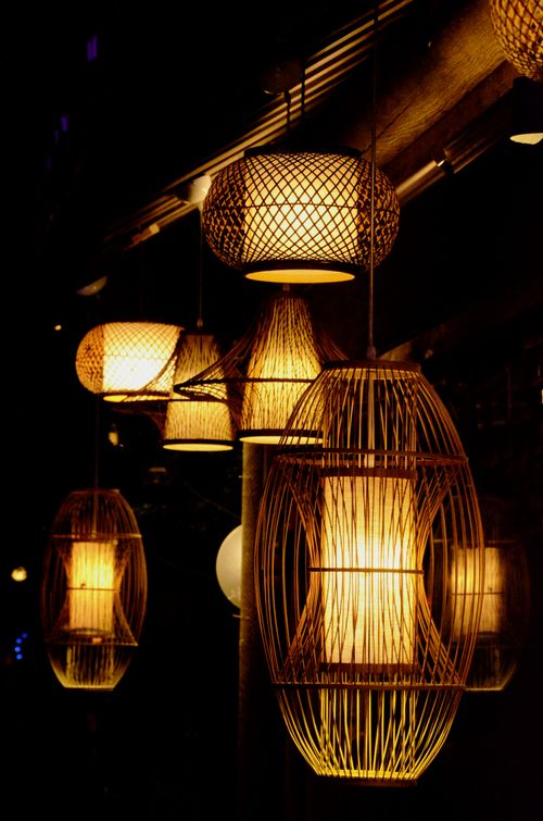 Free A series of bamboo lanterns providing warm illumination in a dark setting, showcasing intricate wicker designs. Stock Photo