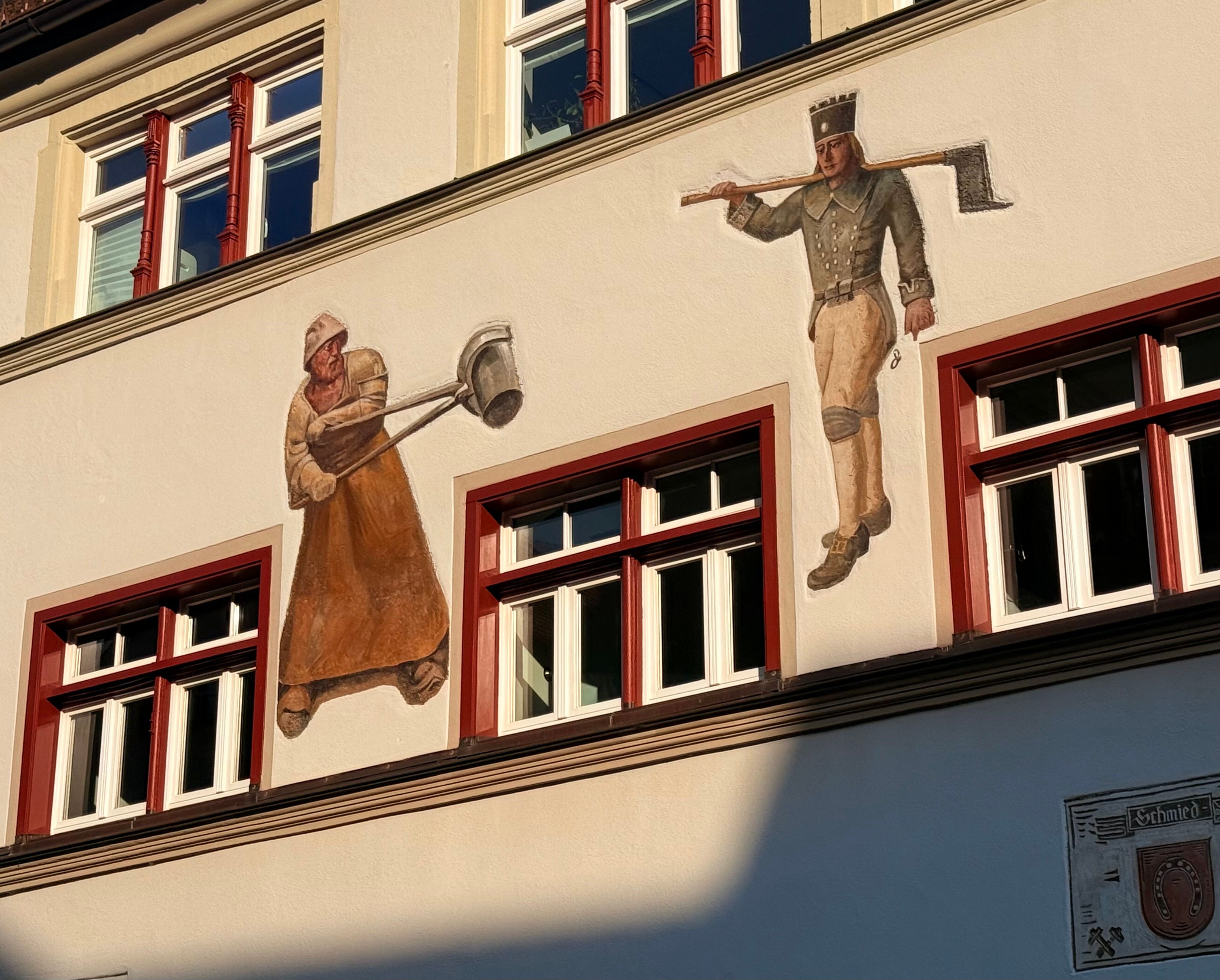 Exterior view of a historic building featuring artistic wall paintings of historical figures.