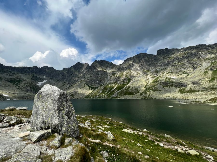 Horské jezero v kamenité kotlině Vysokých Tater pod oblačnou oblohou