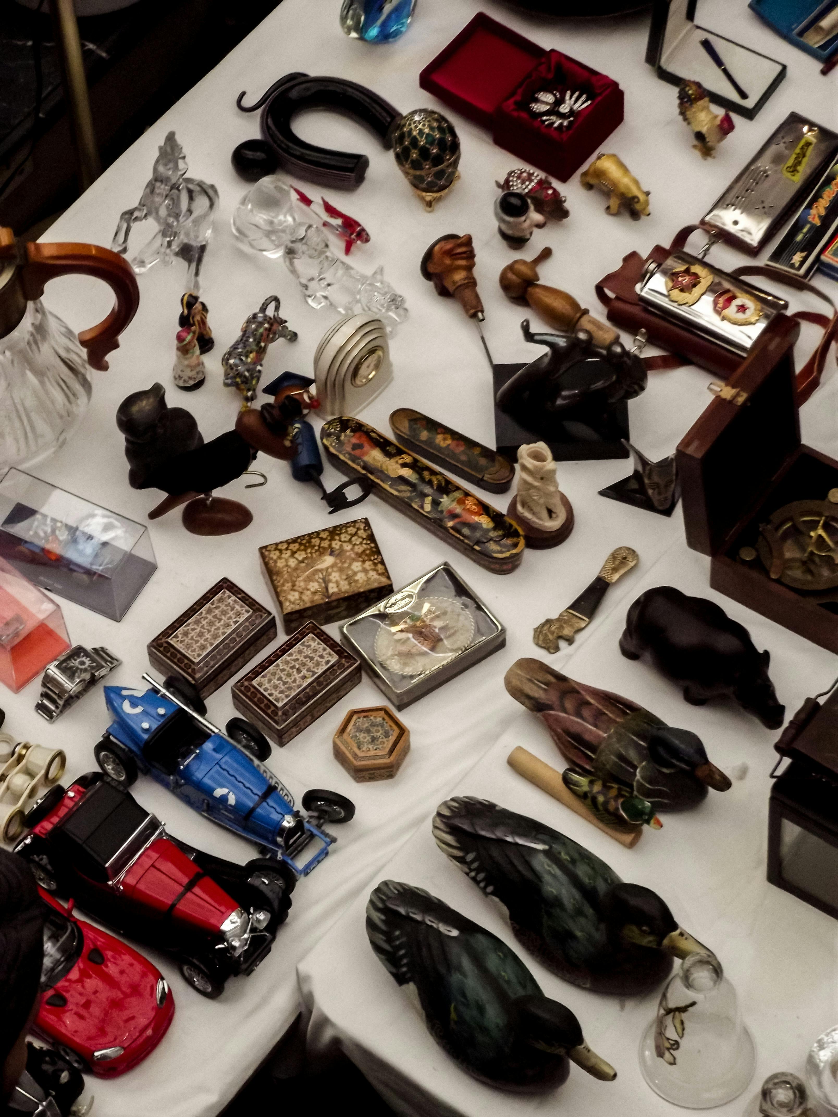 A diverse collection of vintage items and figurines showcased on a white table at a flea market.