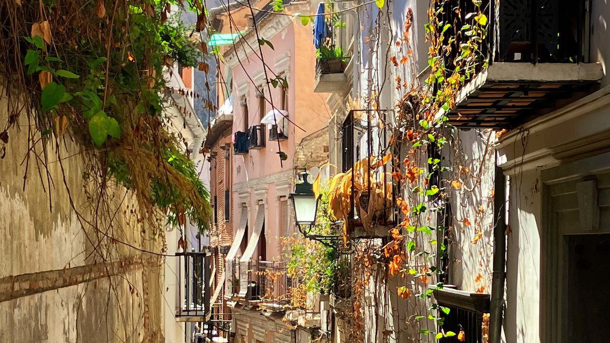 A sunlit narrow street in the old quarter of an Andalusian city in fall 2026