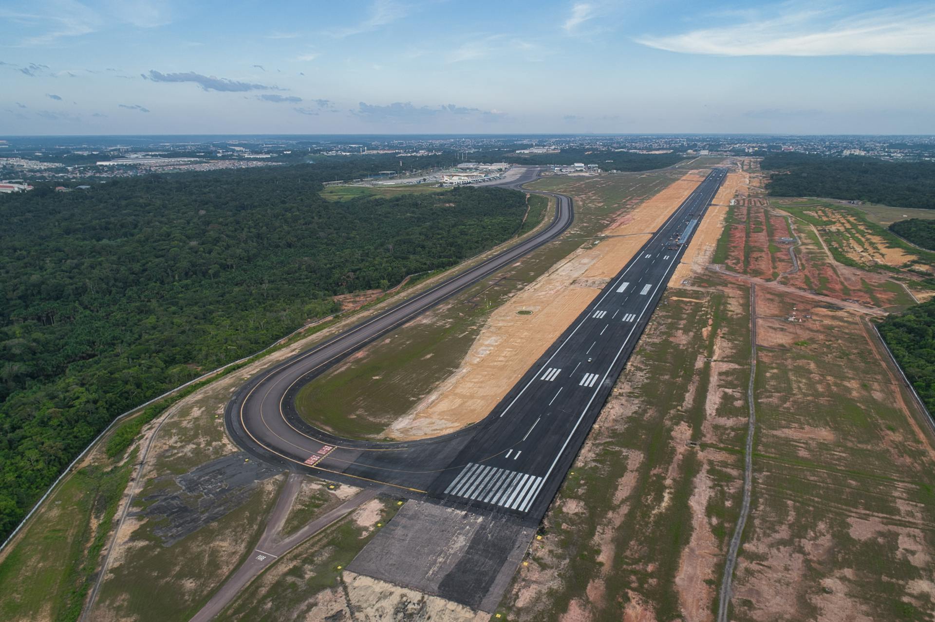 Aerial shot of the Manaus airport runway amidst lush Amazon rainforest.