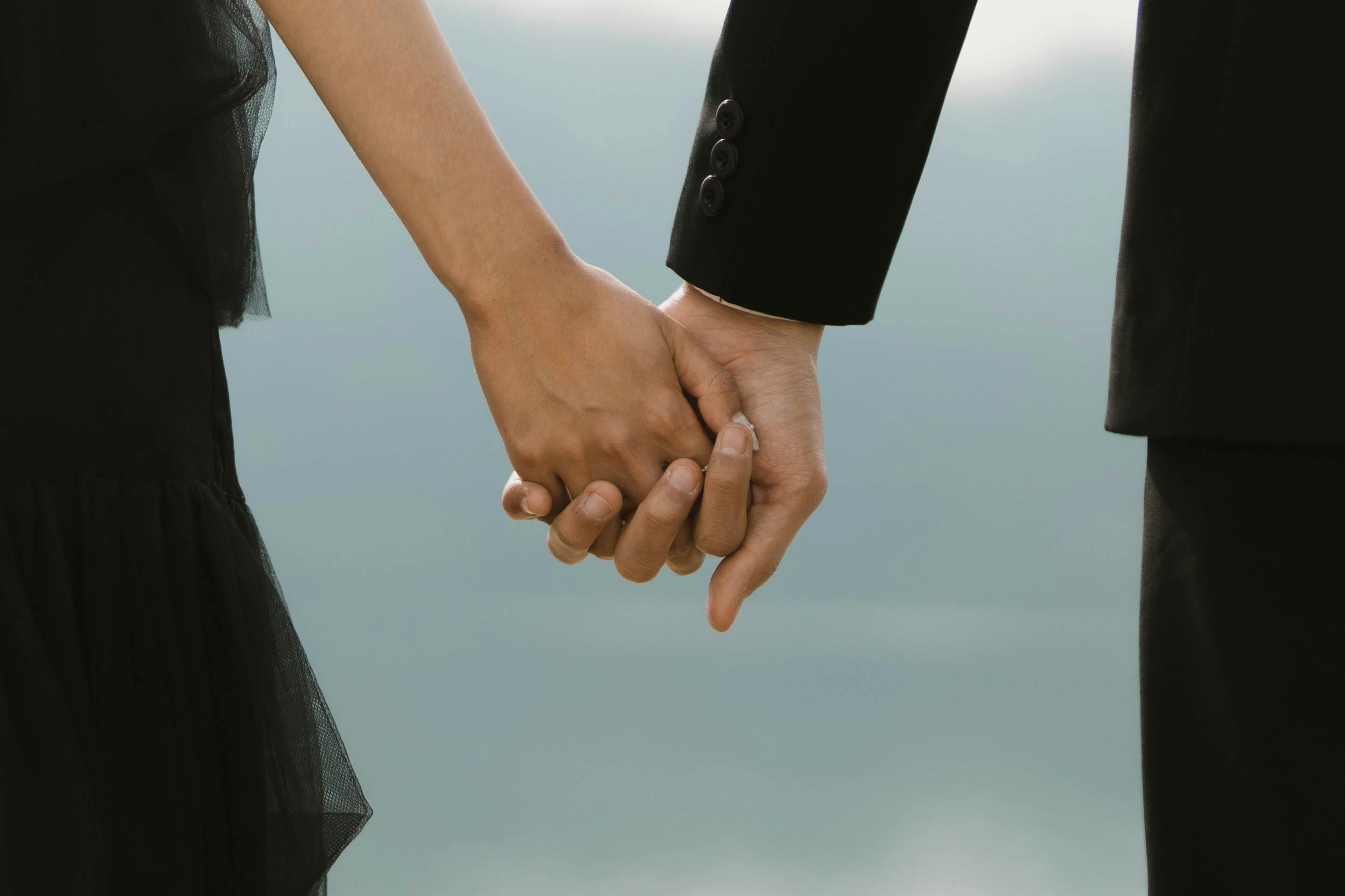 A close-up of a couple holding hands, capturing a romantic moment in Indonesia.