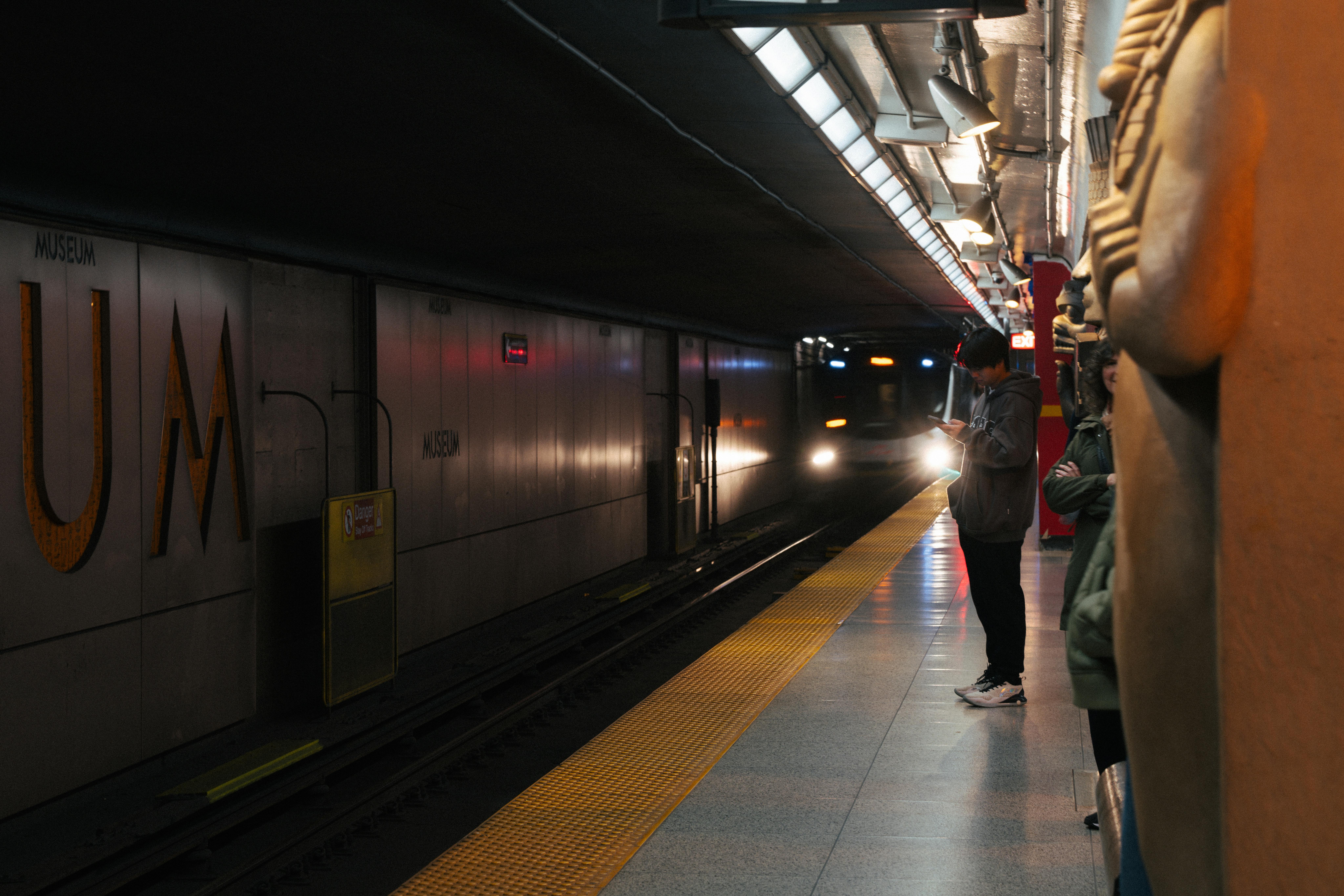 A Toronto Transit Commission (TTC) subway train arriving at a station, with diverse passengers waiting on the platform - housing near York University