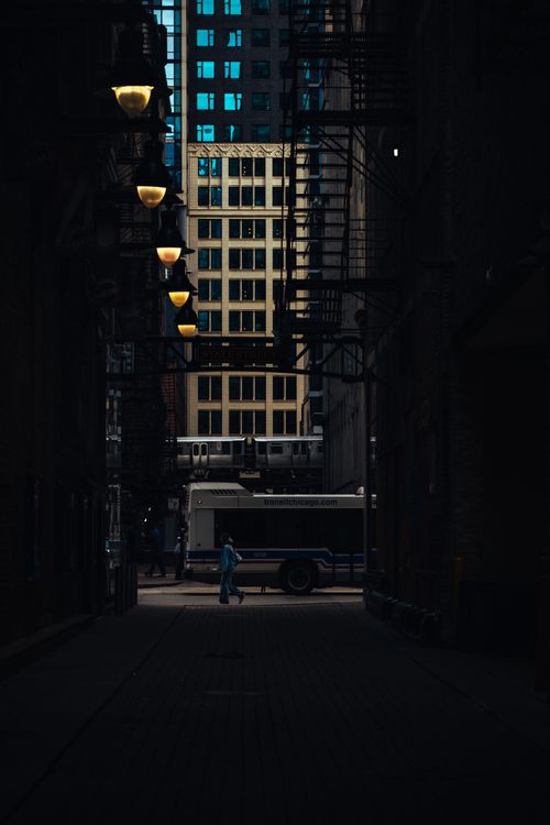 Free Moody urban alley in the city with a distant view of buildings and streetlights at dusk. Stock Photo
