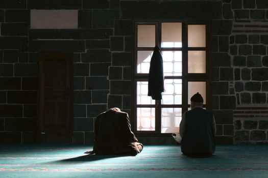Mimari güzelliği ve manevi huzuru bir arada sunan Diyarbakır Ulu Camii'nin içinde namaz kılan iki adam.