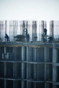 Construction workers at a high-rise building site with visible steel reinforcements.