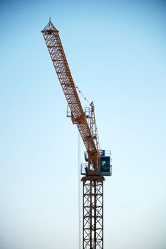 A towering construction crane reaching into a blue sky, symbolizing growth.