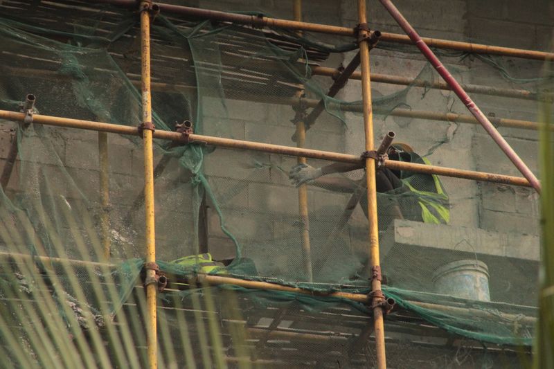 Workers on a building site, secured with scaffolding and safety netting.
